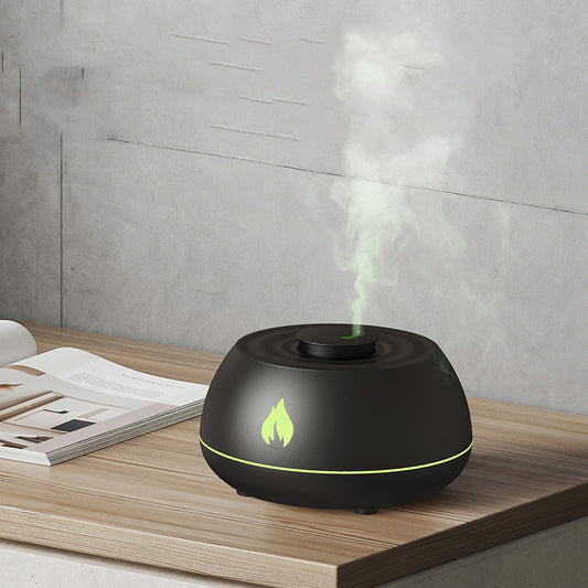 Black essential oil diffuser with green light on a wooden surface